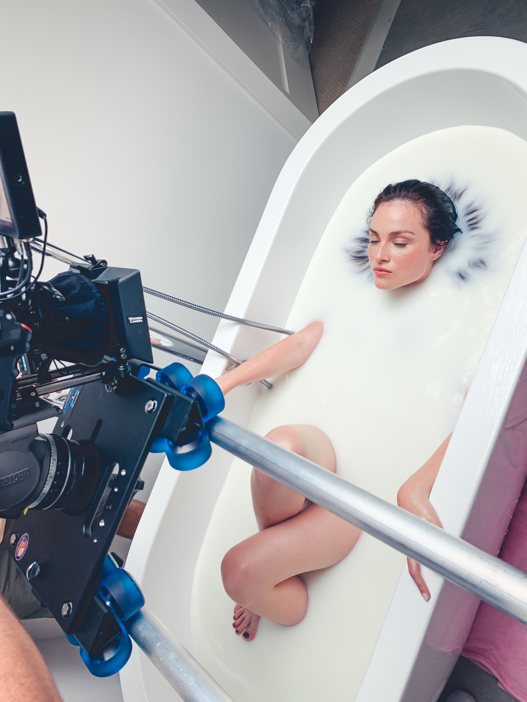 A milk bath skincare shoot from above, the camera rig over the tub